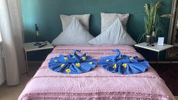 Une chambre à coucher avec un lit, des oreillers, une table de chevet avec une lampe, un miroir et des œuvres d’art murales.