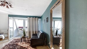 Ein Wohnzimmer mit einer Couch, einem großen Spiegel und Blick durch eine Glastür.