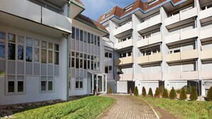 Ein mehrstöckiges Wohngebäude mit Innenhof, Balkonen und einem gepflasterten Weg.