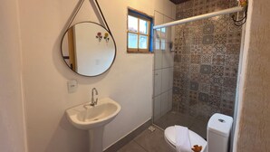 A bathroom with a sink, mirror, toilet, and shower. - Pousada Garden House Tiradentes (Tiradentes)