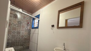 A bathroom with a toilet, a sink, a shower, and a mirror. - Pousada Garden House Tiradentes (Tiradentes)