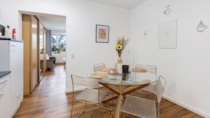 Une cuisine moderne avec un coin repas comprenant une table en verre et des chaises en métal.
