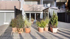 Un bâtiment moderne doté de nombreux balcons, de plantes en pot et d’une entrée sécurisée par un portail.