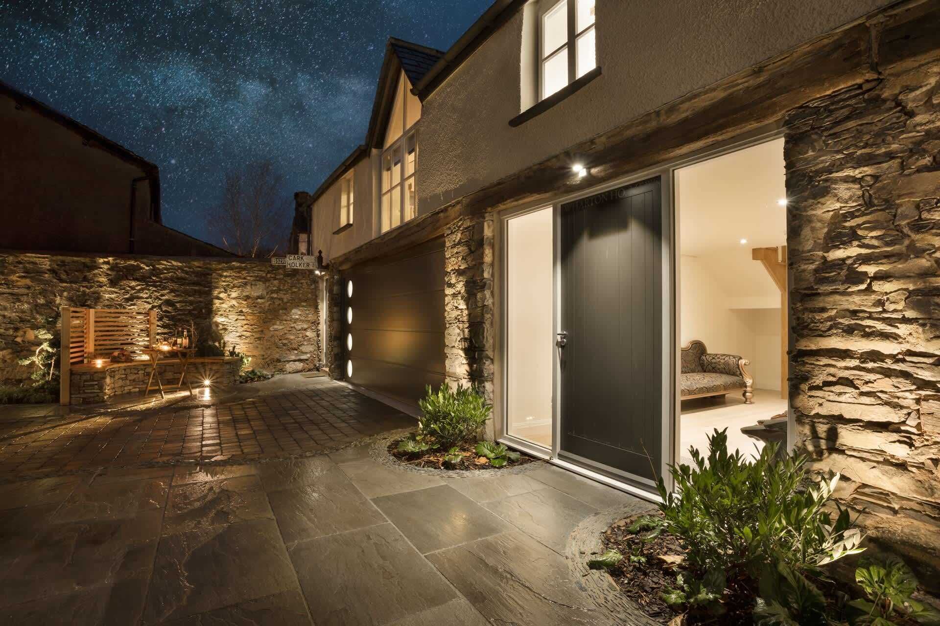 A modern house with a stone exterior, a garage, and a patio area with plants.