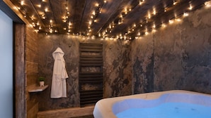 Une salle de spa avec une baignoire, des murs en bois et des guirlandes lumineuses.
