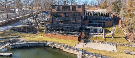 A modern building with multiple floors, outdoor seating, and a small bridge over a water body.