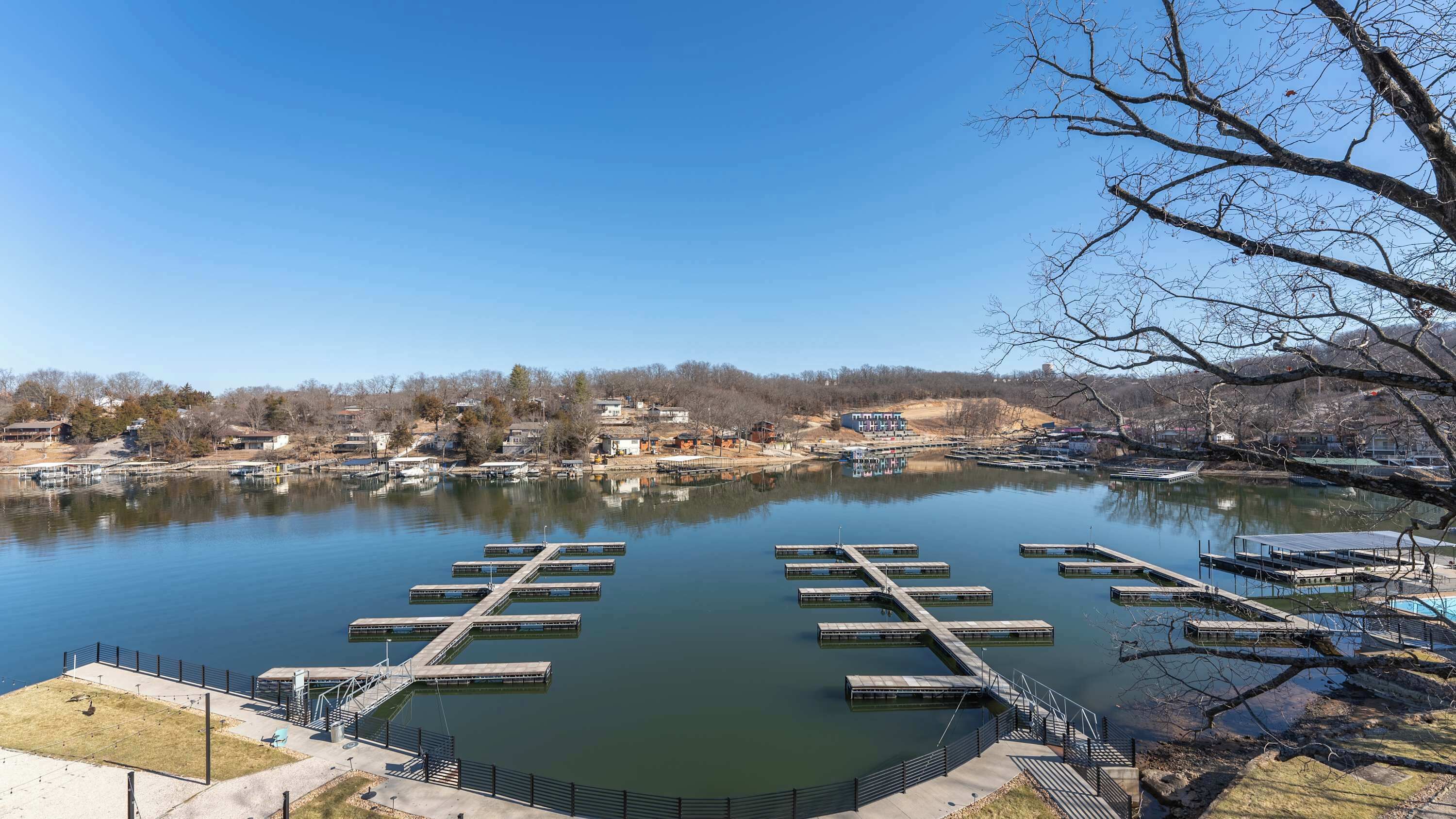 A marina with multiple docks and a clear view of the surrounding area including houses and trees.