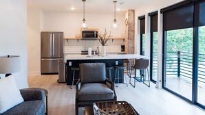 A modern kitchen with a central island, bar stools, and pendant lighting. - Lakeview Loft: Stylish Retreat with Hot Tub & Pool (Osage Beach)