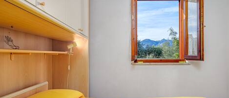 A room with a bed, a window, and a wooden shelf.