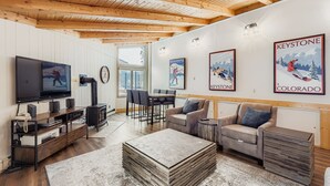 Ein gemütliches Wohnzimmer mit Holzboden, einem Fernseher, einem Kamin und einem Essbereich mit Stühlen und Tisch.