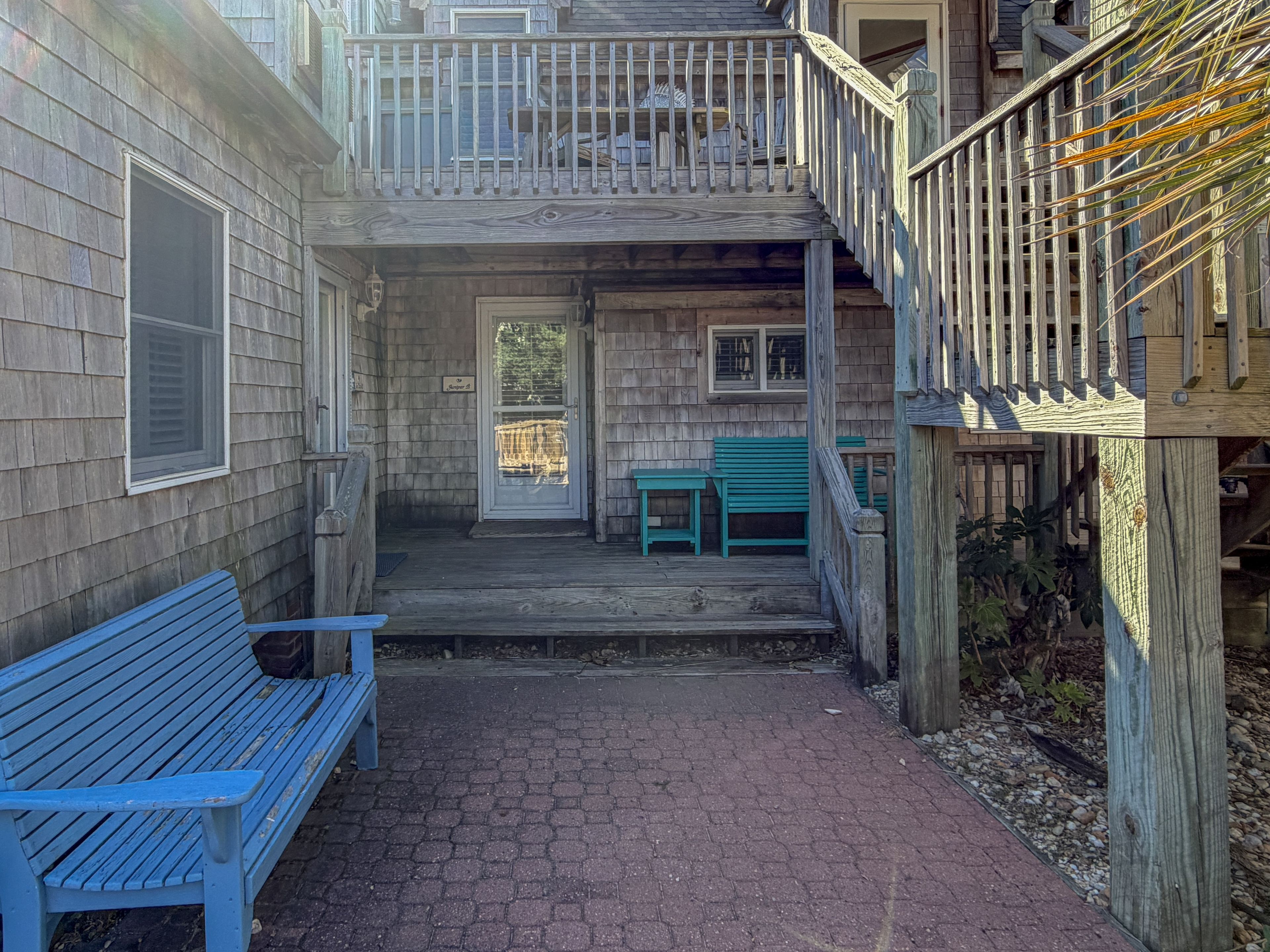 A wooden building with a porch, a blue bench, and a staircase.