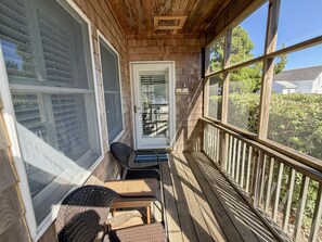 A wooden porch with a door, a small table, and two chairs. - CV1A: Shell Castle A (Ocracoke)