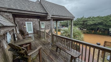 Une terrasse en bois dotée d’un espace salon couvert et offrant une vue sur un jardin aménagé.