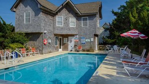 A two-story building with a swimming pool, outdoor seating, and a lifeguard stand.