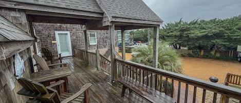 A wooden deck with a covered seating area and a view of a landscaped yard.