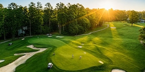 A golf course with sand bunkers, a putting green, and a clubhouse.