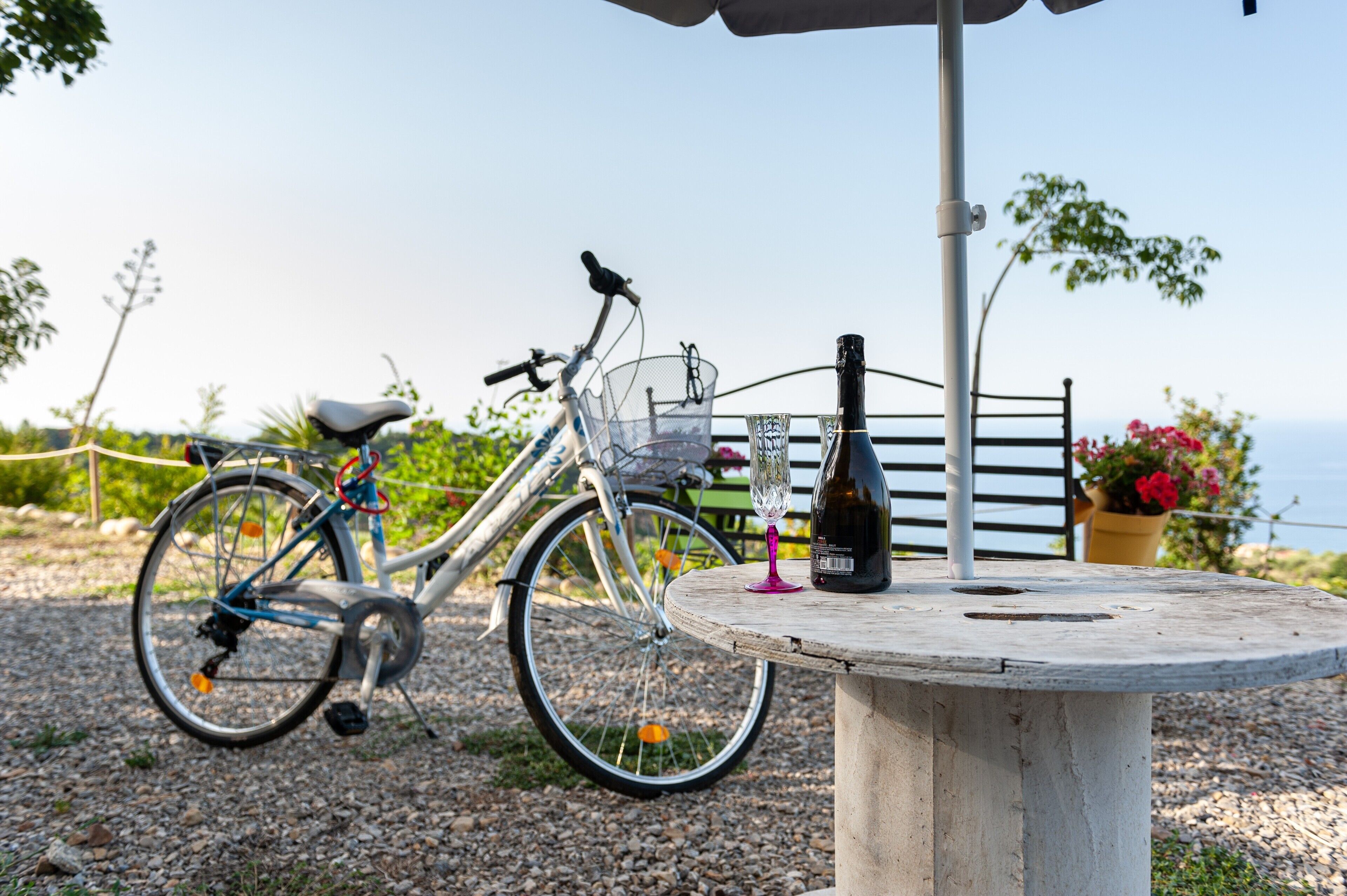 Un vélo est garé à côté d’une table sur laquelle se trouvent une bouteille et un verre.