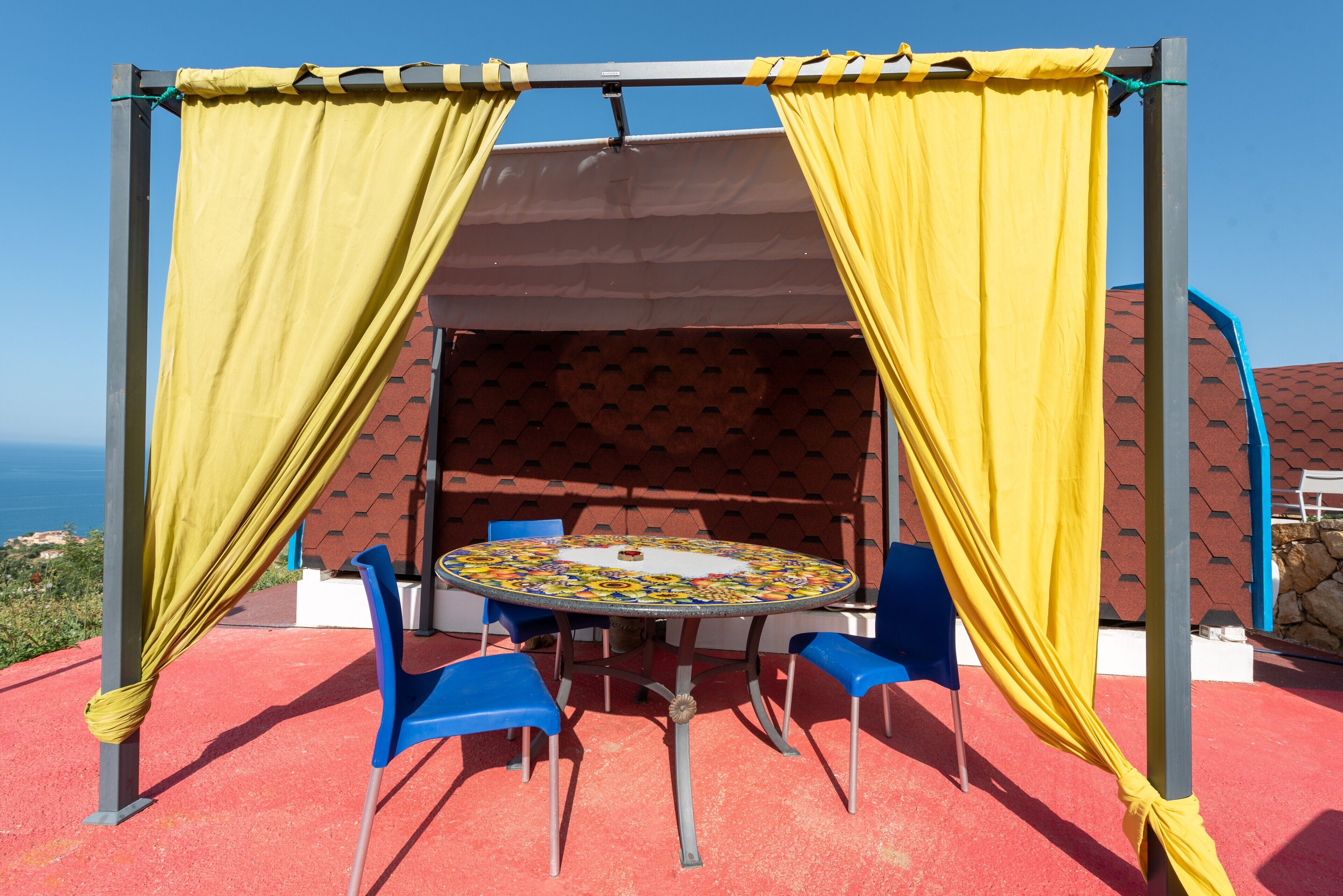 Un'area relax all'aperto con tavolo e sedie, vista sul mare e tetto in tegole.