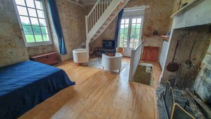 Ein Zimmer mit Holzboden, einem Bett, einem Schlafsofa und einem Fernseher, sowie einer Treppe.