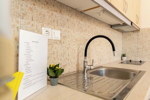 Et moderne køkken med en stålvask, en backsplash af små fliser og en potteplante på bordet.