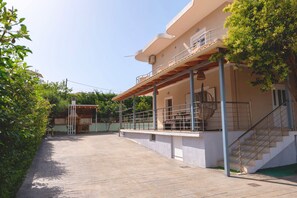A two-story building with a covered patio area, a staircase, and a view of the surrounding greenery. - Dajana Apartments: Your Tranquil Home Base for Exploring Ksamil's Coast. (Ksamil)