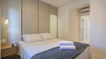 A modern hotel room with a bed, bedside table, and a mirror.