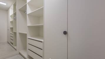 A walk-in closet with open shelving and drawers, a door with a handle, and a light fixture on the ceiling.