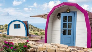 Two small, colorful cabins with a stone pathway leading to them, set against a hilly landscape. - Bungalow 'Limone' with Sea View, Wi-Fi and Air Conditioning (Tusa)