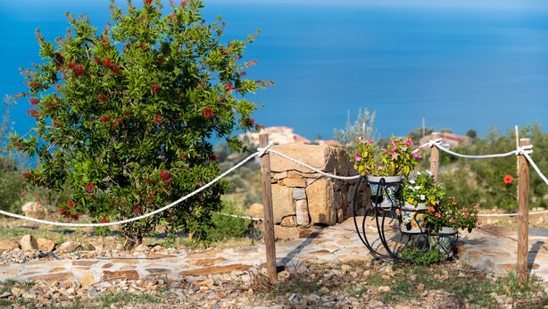 A stone pathway leading to a stone wall with a potted plant and a rope barrier. - Bungalow 'Limone' with Sea View, Wi-Fi and Air Conditioning (Tusa)