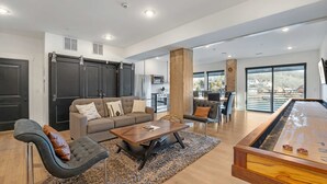 Amplia sala de estar con sofá, sillones, una mesa de centro y una mesa de billar.
