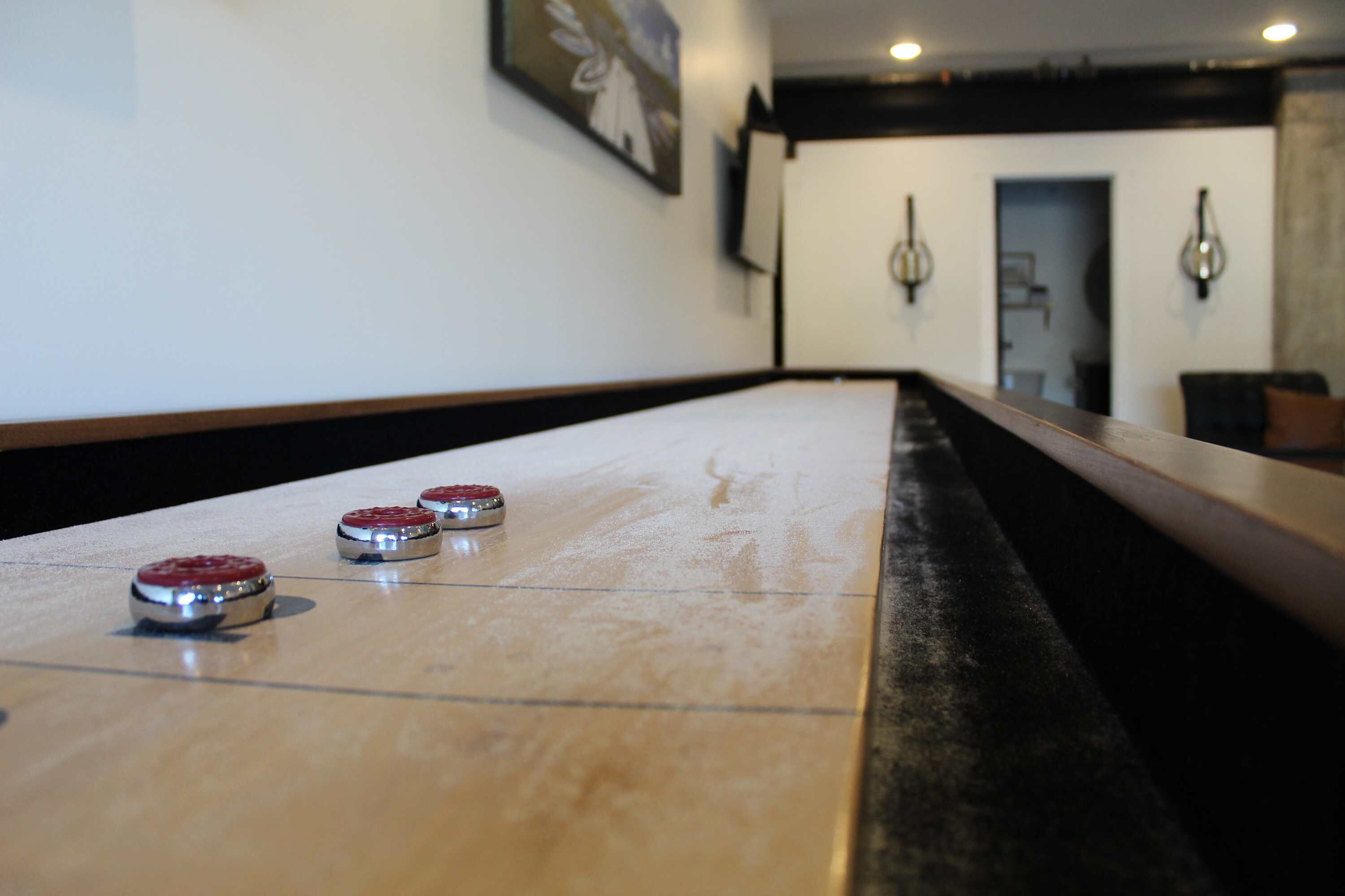 A shuffleboard table with three pucks in a hotel lobby.