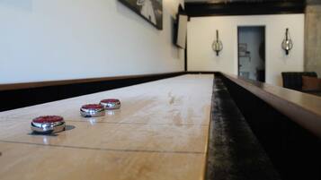 A shuffleboard table with three pucks in a hotel lobby.