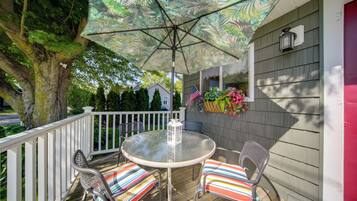 A deck with a table and chairs, an umbrella, and a lantern.