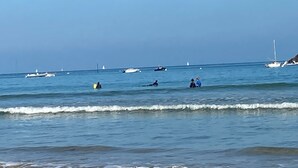 Une plage avec une eau calme, des bateaux et des gens.