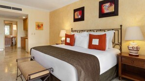 Una camera d'hotel con un letto grande, due comodini con lampade, una poltrona e opere d'arte alle pareti.