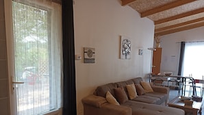 Ein Wohnzimmer mit einer Sofagarnitur, einem kleinen Tisch und einem Fenster mit Vorhängen.