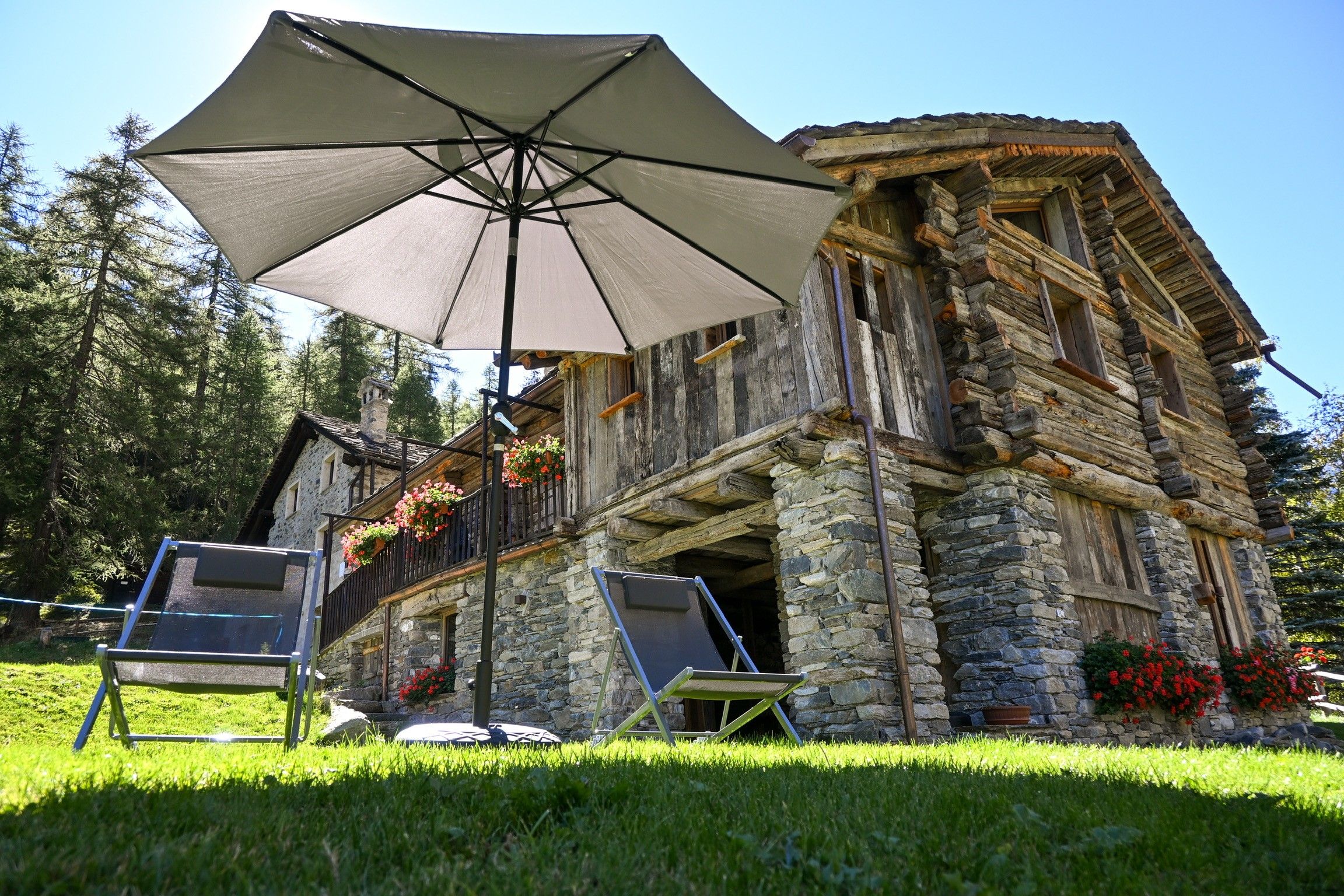 Un bâtiment en pierre doté d’un balcon et d’un grand parasol.