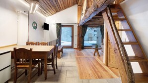 A dining area with wooden furniture, a TV, and a view of the outside.
