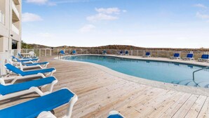 Un espace piscine avec des chaises longues bleues et une terrasse en bois.