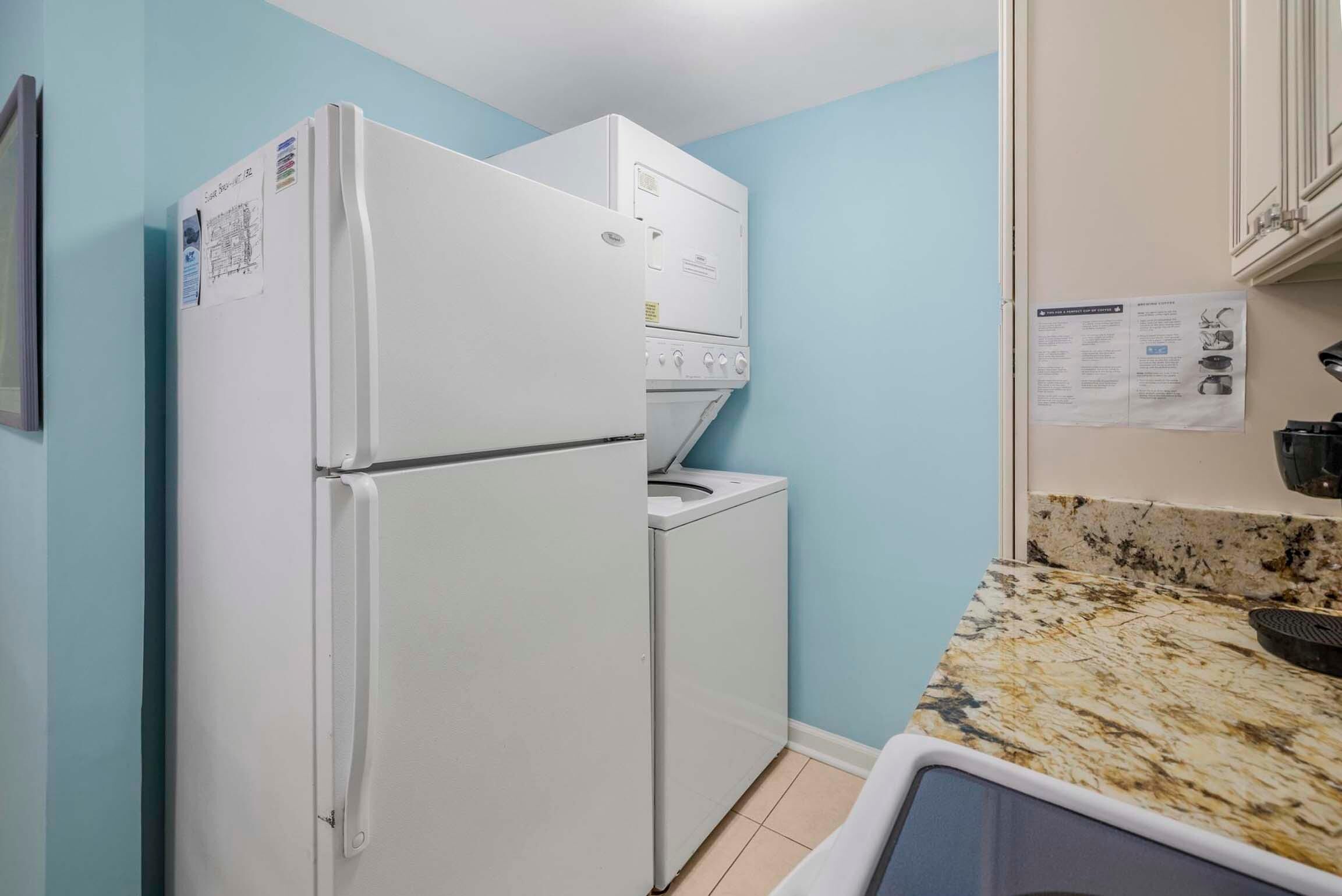 A compact kitchen with a white refrigerator, a built-in oven, and a washing machine.