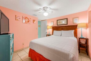 A bedroom with a bed, a ceiling fan, a television on a cabinet, and artwork on the walls. - Sugar Beach 132 (Orange Beach)