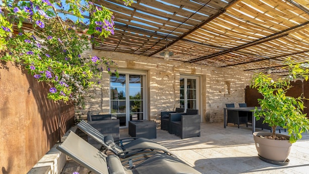 Eine Terrasse im Freien mit einer Pergola, Sitzgelegenheiten und einem Blumentopf.