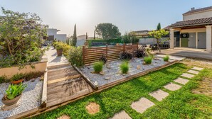 Ein Garten mit einer Holzterrasse, einem Pool und einem Gebäude mit einem Ziegeldach.