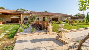 A house with a tiled roof, a patio with a stone table, and a garden with various plants. - Holiday Home “Gîte Genêt - Villa Cassandra” with Shared Pool, Wi-Fi and Air Conditioning (Tavel)