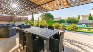 An outdoor patio with a covered seating area, a table, and chairs. - Holiday Home “Gîte Genêt - Villa Cassandra” with Shared Pool, Wi-Fi and Air Conditioning (Tavel)