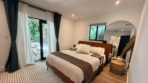 Quarto moderno com uma cama grande, um espelho e vista para o exterior.