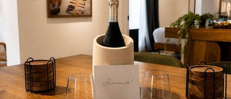 A wooden table with a bottle of champagne, two glasses, and a 'Bienvenidos!' card.