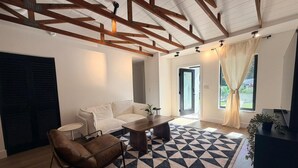 A modern living room with a geometric patterned rug, a sofa, a coffee table, and a TV stand. - Modern Rustic Miami Retreat | Tree-Shaded Backyard & Fire Pit | Near Wynwood (Miami)