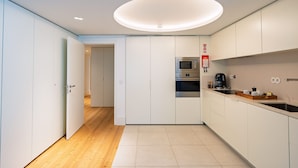 A modern kitchen with white cabinets, a microwave, and a coffee machine. - Bolhão Prime | Luxe 3BR + Garage (Oporto)