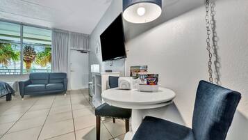 Habitació d'hotel moderna amb una finestra gran, televisió de pantalla plana, taula rodona de dinar i un sofà.